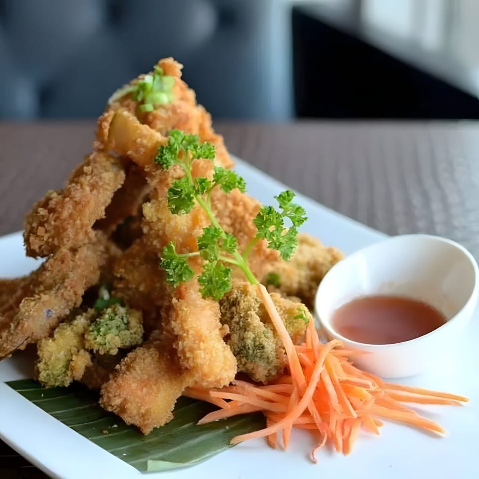 Crispy fried Thai appetizers, garnished with parsley and shredded carrots, served with dipping sauce.