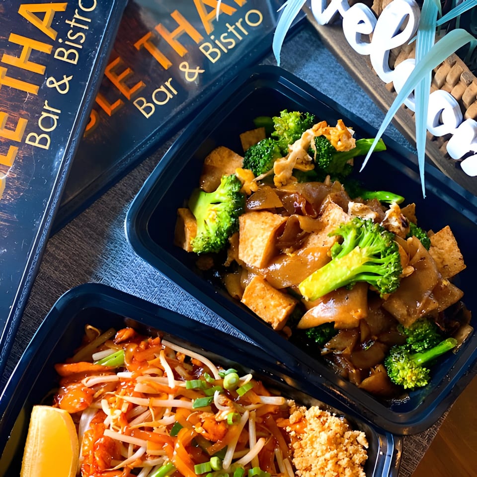 Two Table Thai Bar & Bistro takeout containers with Pad See Ew and Pad Thai.