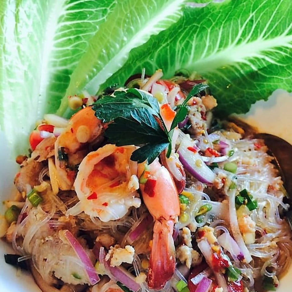 Close-up of a Thai glass noodle salad with shrimp, minced pork, red onion, and lettuce.