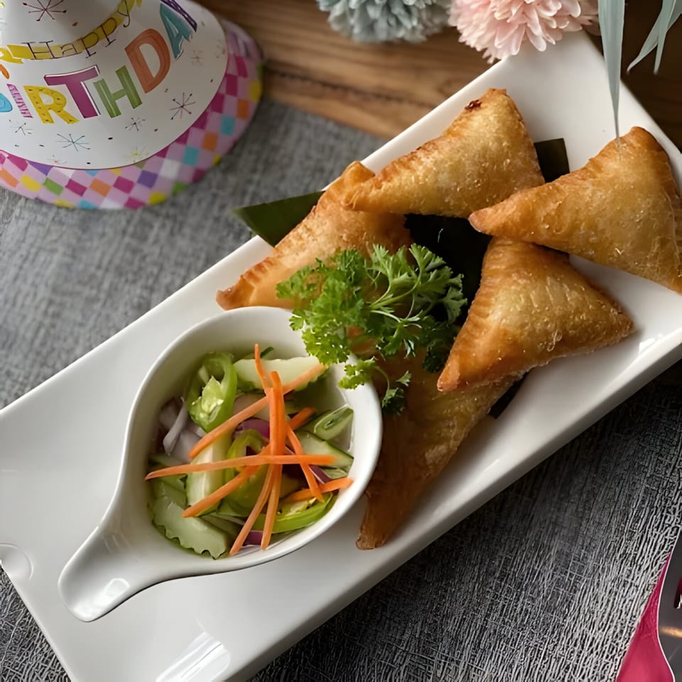 Golden-fried Thai samosas with a side of pickled vegetables and a birthday hat.