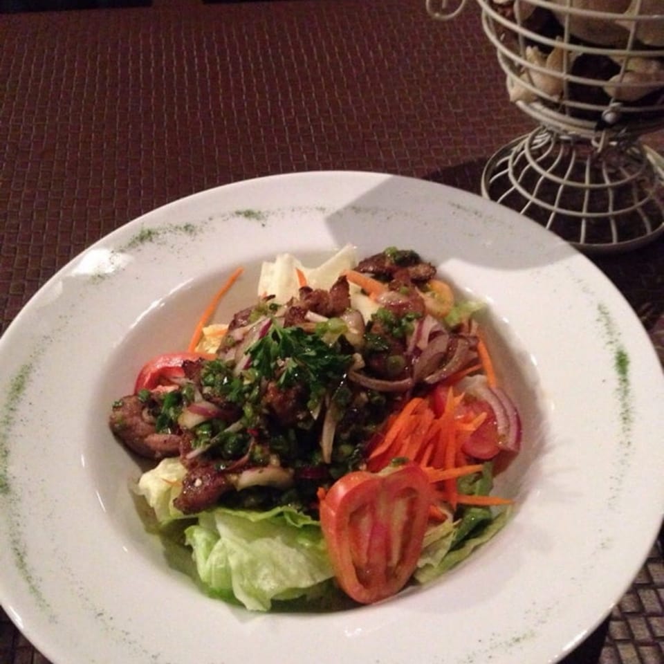 Table Thai Bar & Bistro's Thai beef salad with lettuce, tomatoes, carrots, and onions.
