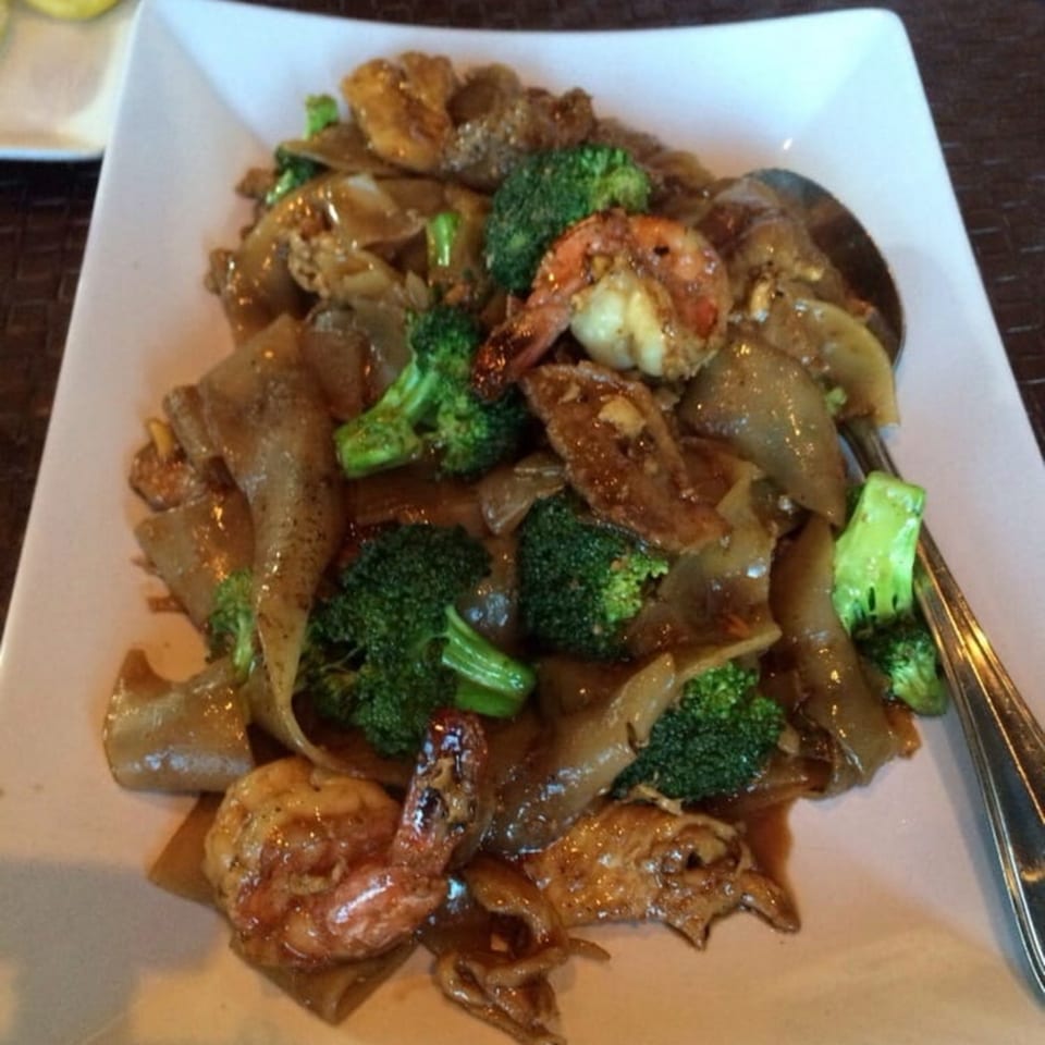 Table Thai Bar & Bistro's Pad See Ew with shrimp and broccoli on a white plate.